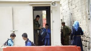 Israelisk soldat kontrollerar elevers skolväskor vid checkpoint 56 i Hebron Soldat kontrollerar elevers skolväskor i Hebron