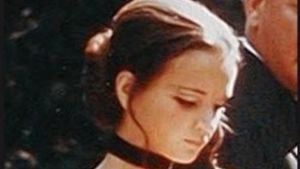 Christina Lindberg i filmen Rötmånad (1970) Närbild på skådespelaren Christina Lindberg som står i en svart urringad dräkt och läser en lapp.