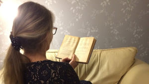 Nainen lukee kirjaa tohvelit vieressään