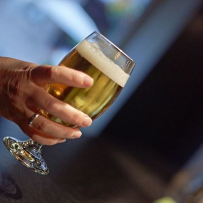 Glass of beer held in a woman's hand.