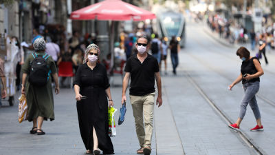 Människor med ansiktsskydd som promenerar på en gata i Jerusalem.