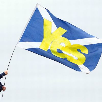 Poika pitelee Skotlannin lippua, jossa lukee "Kyllä".