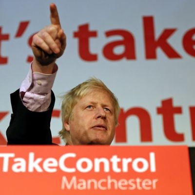 Boris Johson osoittaa puhujakorokkeelta sormella yleisöä. Puhujapöntössä on teksti, joka kehottaa ottamaan vallan itselle.