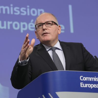 Frans Timmermans käsi pystyssä puhujapöntössä.