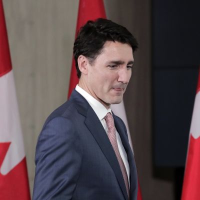 Kuvassa Kanadan pääministeri Justin Trudeau. Hänen takanaan on kolme Kanadan lippua.