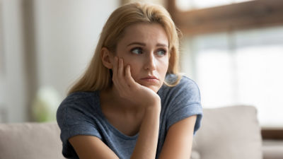 Blond kvinna lutar hakan i handen och ser fundersam ut
