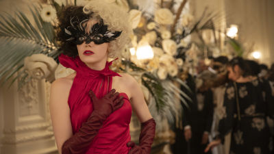 Cruella (Emma Stone) ser förvånad ut i en röd galadress på en maskerad.