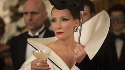 Närbild på baronessan Hellman (Emma Thompson) med ett champangeglas i handen.
