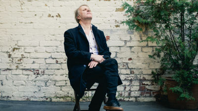 Måns Strömberg, DJ Bunuel, sitter med slutna ögon på en stol med tegelvägg i bakgrunden. 