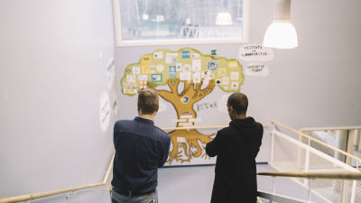Lloyd Libiso ja Jussi Roms katselevat yhdessä koulun seinään maalattua oppimisen puuta.