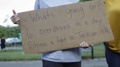 En person håller en skylt under en demonstration. På skylten står "Vad är det som pågår? Sex överdoser på ett dygn."