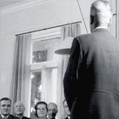 Mies seisoo mustavalkoisessa kuvassa ihmisjoukon edessä