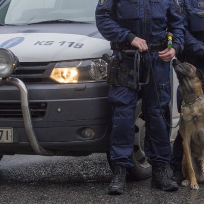 Poliisikoira ja -auto sekä kaksi poliisia.