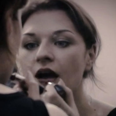Nuori nainen laittaa huulipunaa. Kuva dokumentista Suomi on kaunis sana (2004).