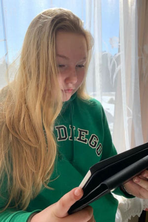 Nelly Lehtinen studerar till närvårdare delvis på distans. En ung kvinna läser något från en surfplatta.