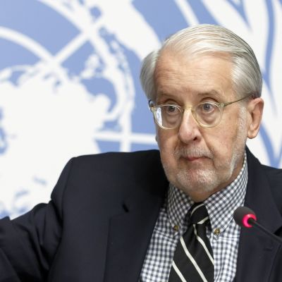 Paulo Pinheiro käsi pystyssä YK:n tunnuksen edessä.
