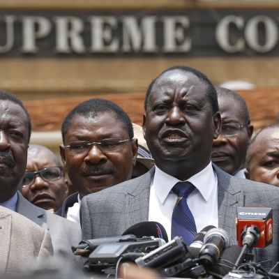 Raila Odinga puhumassa mikrofoniin. Hänen taustallaan seisoo useita saman puolueen poliitikkoja.