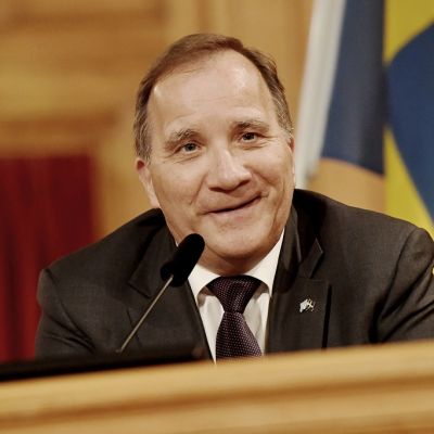 Hymyilevä Löfven taustallaan Ruotsin lippu.