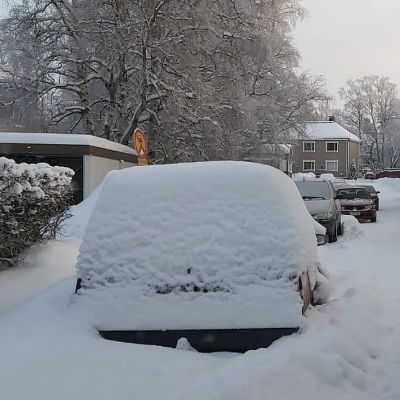 Kuvassa lumeen hautautunut auto tien varrella