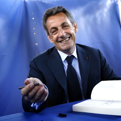 Nicolas Sarkozy katsoo kameraan ja virnistää.