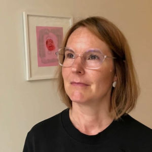 Psykoterapeuten Anna Collander säger att Vastaamo inte tagit det ansvar som bolaget borde ha tagit. En kvinna vid en vägg med tavlor.
