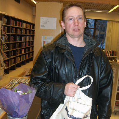 Mies seisoo kirjastossa kassi kädessään.