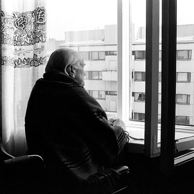 Vanha nainen katselee ikkunasta ulos.