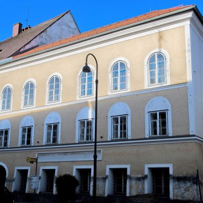 Kellertävä kivirakennus, jossa on kaari-ikkunat ja punainen katto.