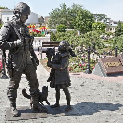 Patsas esittää asetta olallaan kantavaa hymyilevää sotilasta ja tyttöä, joka ojentaa hänelle kukkapuskaa.