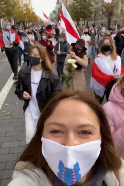 En kvinna med munskydd framför en protestmarsch