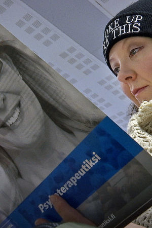 Nainen lukee Helsingin psykoterapiainstituutin esitettä.