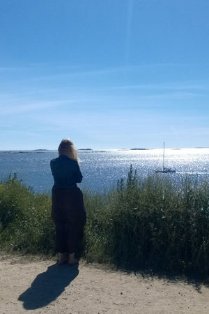 Nainen tuijottaa merelle.