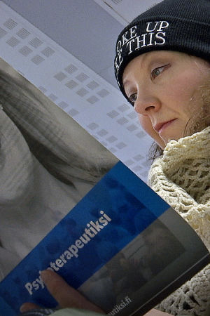 Nainen lukee Helsingin psykoterapiainstituutin esitettä.