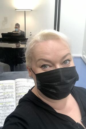 Oopperalaulaja Johanna Rusanen-Kartano mustassa maskissa, taustalla Kansallisoopperan harjoituspianisti Hans-Otto Ehrström.
