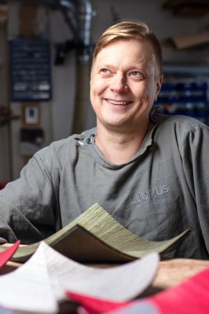 Ville Naumanen istuu puusepänverstaalla, etualalla puuesineitä.