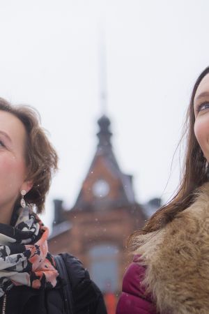 Pirjo ja Saija Viherlaakso seisovat ulkona, katsovat yläviistoon hymyillen.