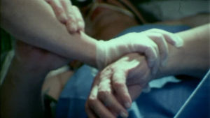 Sairaanhoitaja pitää vuoteessa makaavaa potilasta käsivarresta kiinni 1979
