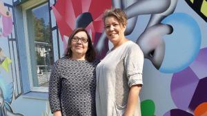 Sari Myllymäki och Mona Stenman, ansvariga förmän vid Stjärnhem. Målningen är skapad av Reetta Hiltunen tillsammans med hemmets invånare. Sari Myllymäki och Mona Stenman har ansvaret vid Stjärnhem i Esbo. Baskom dem en muralmålning av Reetta Hiltunen, skapad tillsammans med hemmets invånare, de boende.