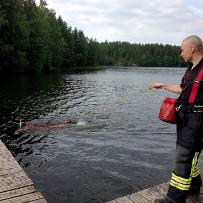 Pelastuslaitoksen narumies varmistaa että pintapelastaja ui oikeaan suuntaan harjoituksessa Suolijärvellä