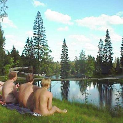 Neljä alastonta ihmistä istuu ruohikolla.