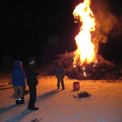 Kolme ihmistä katsoo pääsiäiskokkoa.