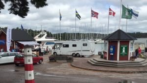En husbil letar efter vattenpåfyllning vid Nagu gästhamn. En husbil kör upp bland flaggstångarna vid Nagu gästhamn