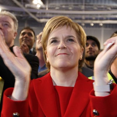 Hymyilevä Sturgeon taputtaa käsiään puoluetoverien ympäröimänä.