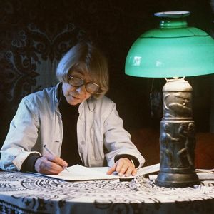 Kirjailija ja taiteilija Tove Jansson kirjoittaa pöydän ääressä.