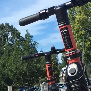 Tre elsparkcyklar står vid sidan av en trottoar.