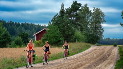 Tre kvinnor cyklar i Nagu på Skärgårdens ringväg.
