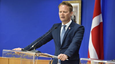 Danmarks utrikesminister Jeppe Kofod håller tal med Danmarks flagga i bakgrunden.