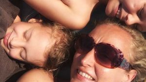 Ulrika tillsammans med sina två döttrar, Matilda och Frida. En kvinna ligger på en handduk tillsammans med sina två döttrar.