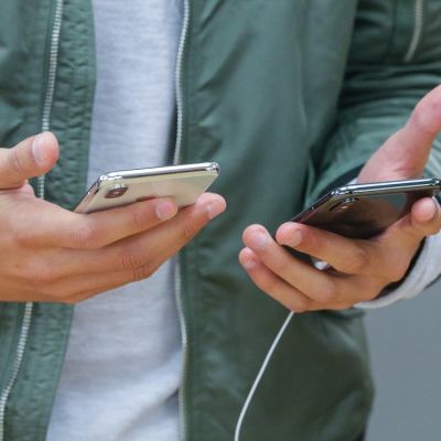 Miehen käsissä iPhone-kännykät.