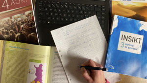 Enligt Alva var det betydligt svårare att studera på distans än i skolan. gymnasoeböcker och en dator som illustrerar studier på distans